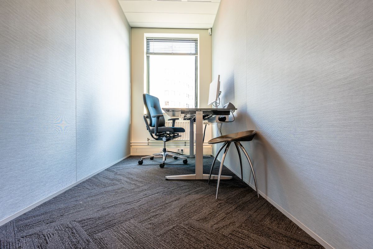 Petit bureau lumineux avec un poste de travail, un fauteuil et un tabouret devant une fenêtre