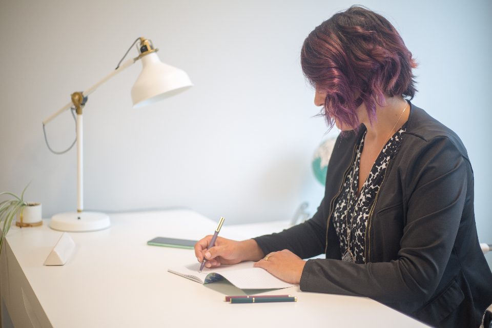 Une professionnelle prend des notes à son bureau